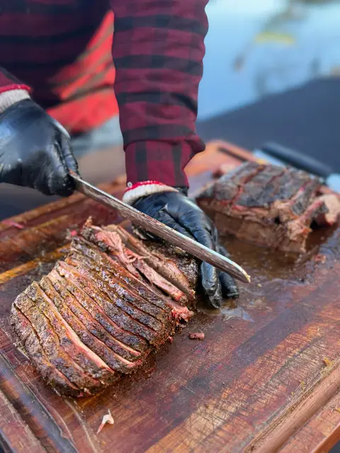 Slicing oak-smoked beef brisket on a cutting board